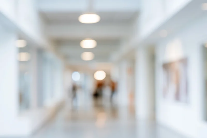 Blurred interior of a modern office hallway with circular ceiling lights and white walls