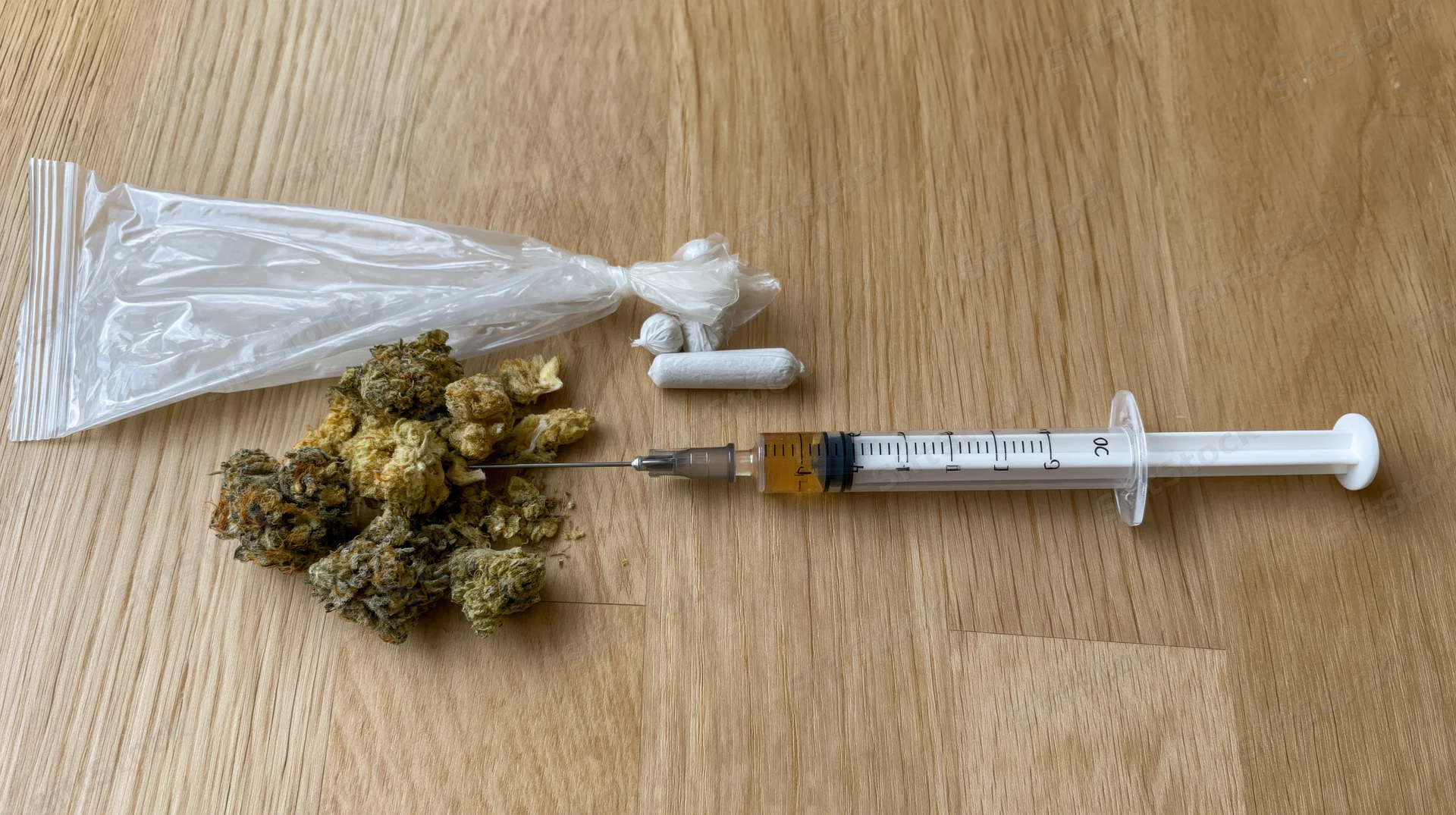 Cannabis buds and syringe with pills on wooden table