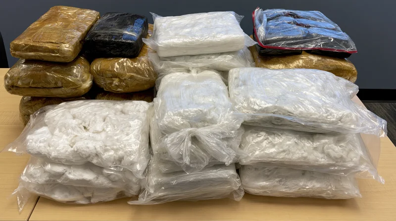 Stacks of vacuum-sealed drug bundles arranged on a wooden table in an office setting