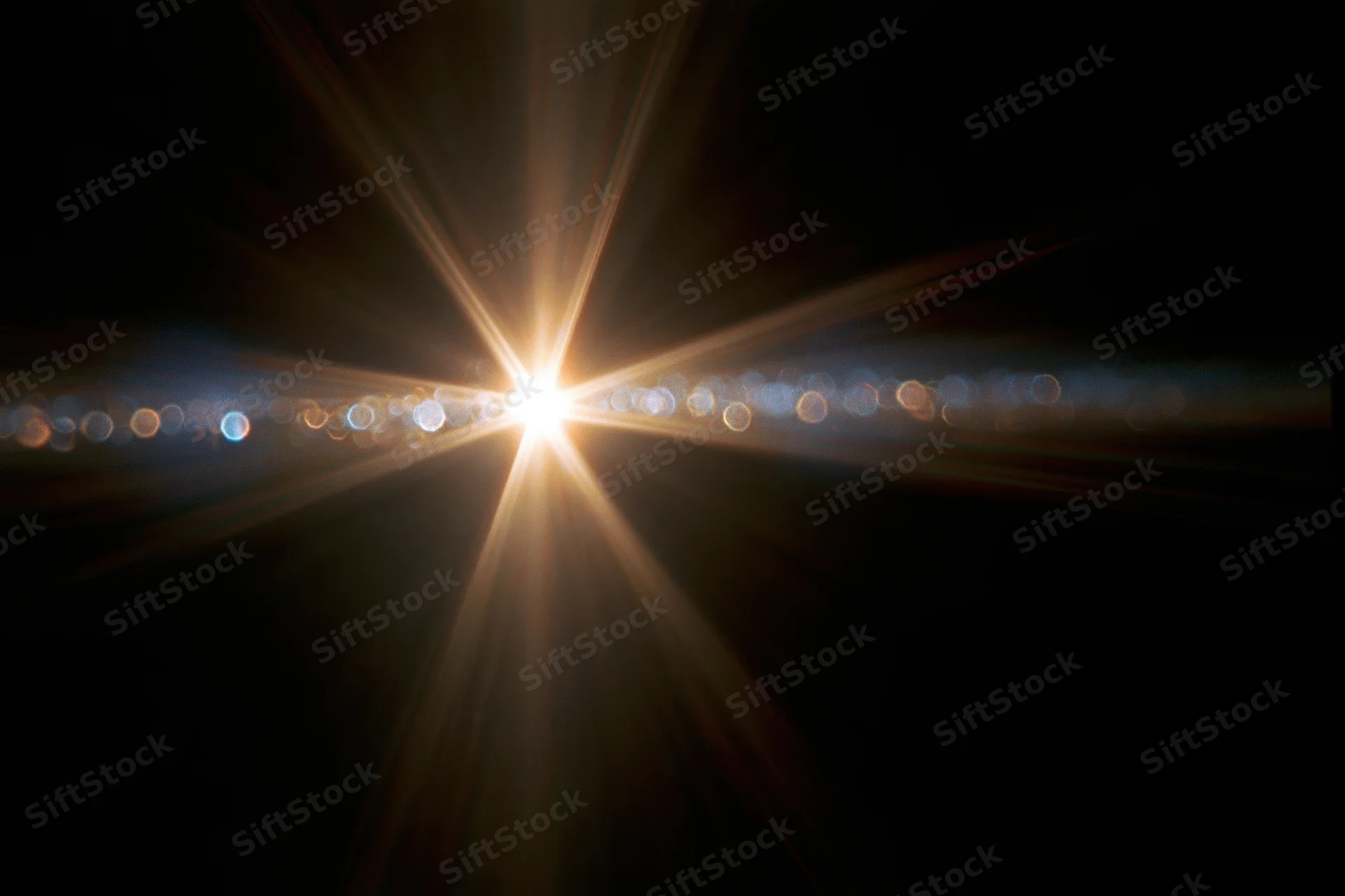Intense lens flare from a single bright light source in dark background with radial beams and bokeh circles