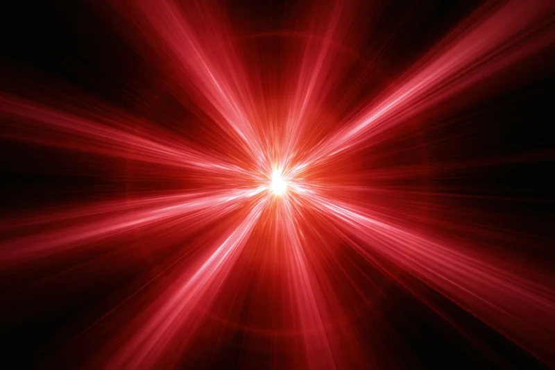 Intense red light burst radiating outward from a bright central point in a dark space
