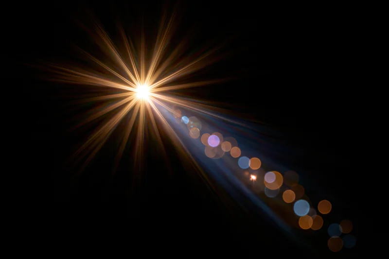Intense light source emitting starburst rays with bokeh circles against dark background
