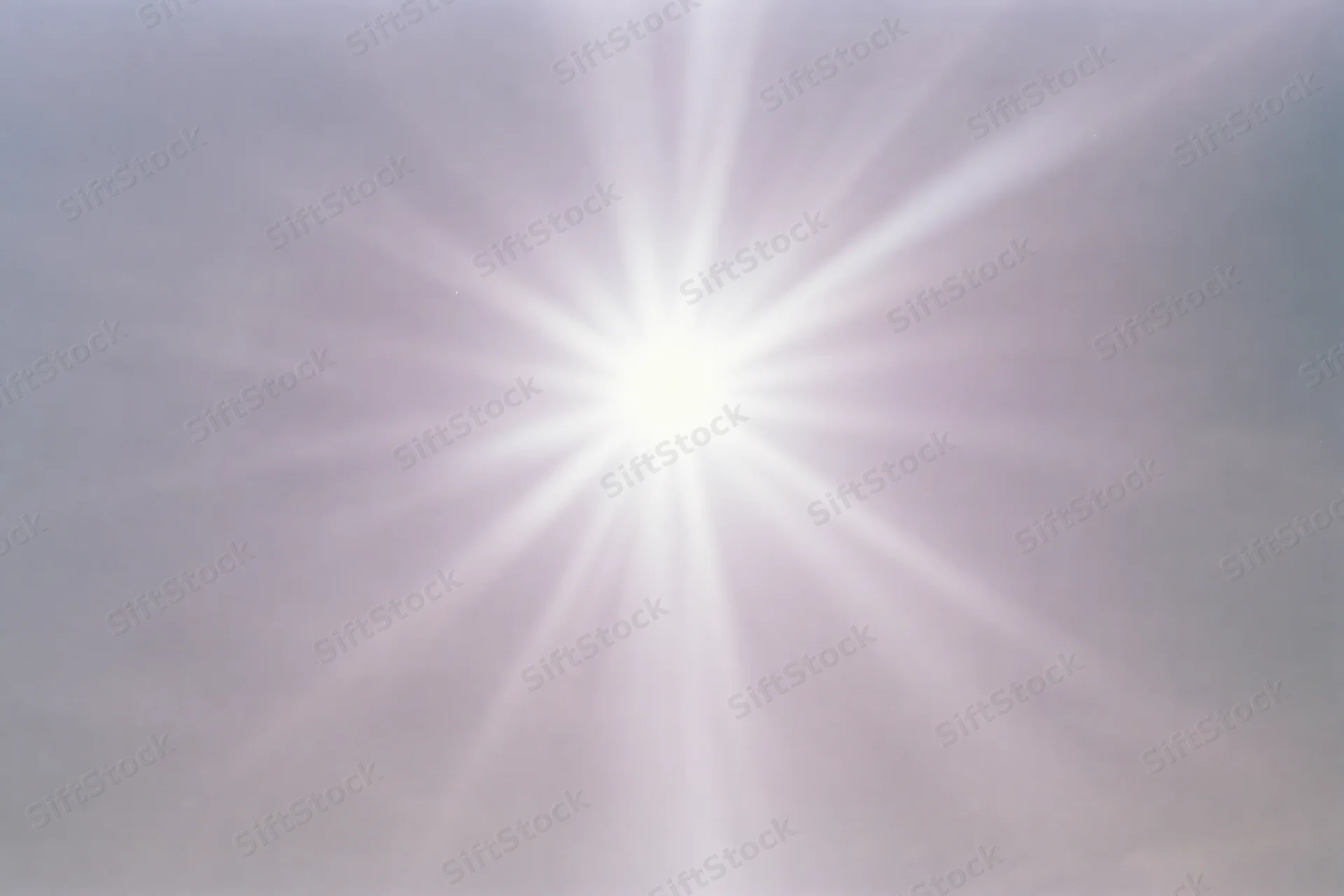 Intense sun flare bursting from upper center of the sky