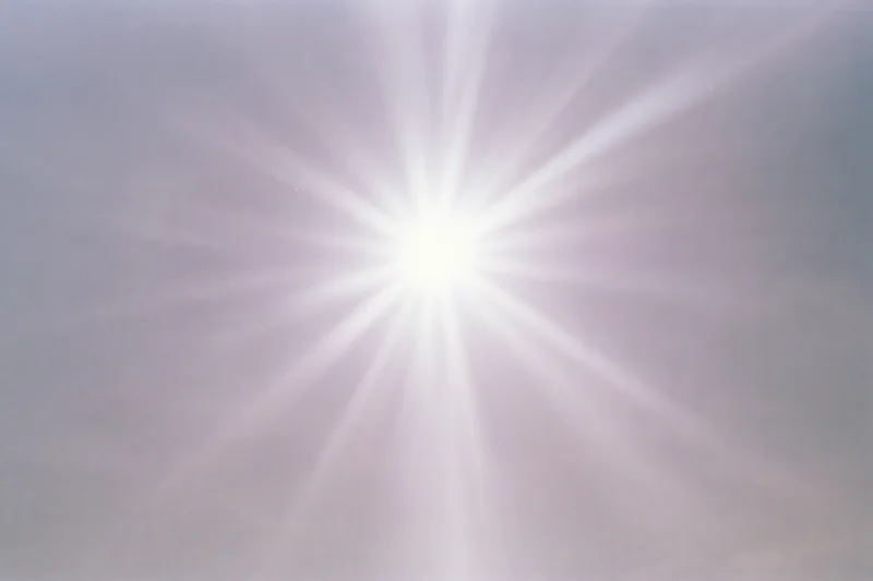 Intense sun flare bursting from upper center of the sky