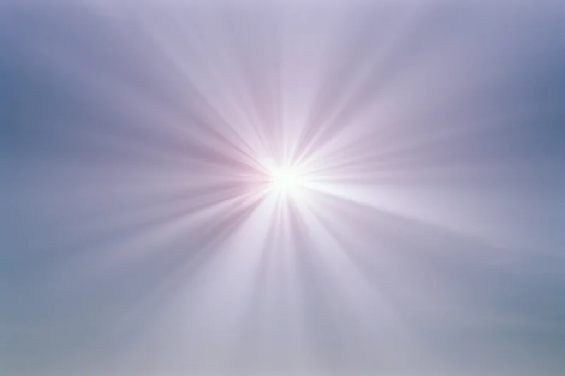 Intense sun flare bursting from center of sky with radiating light beams