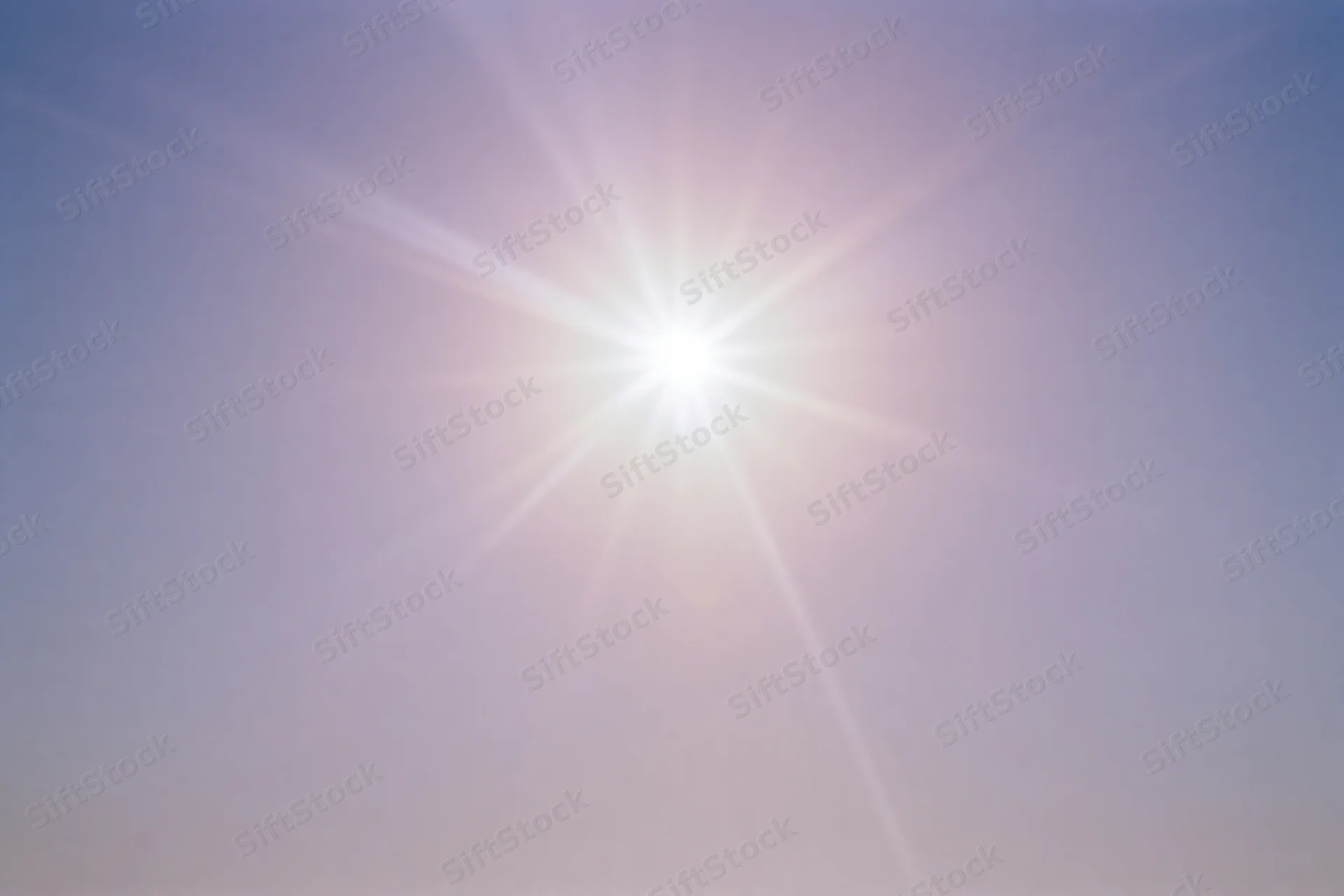Intense sun flare bursting from upper center of frame against clear sky