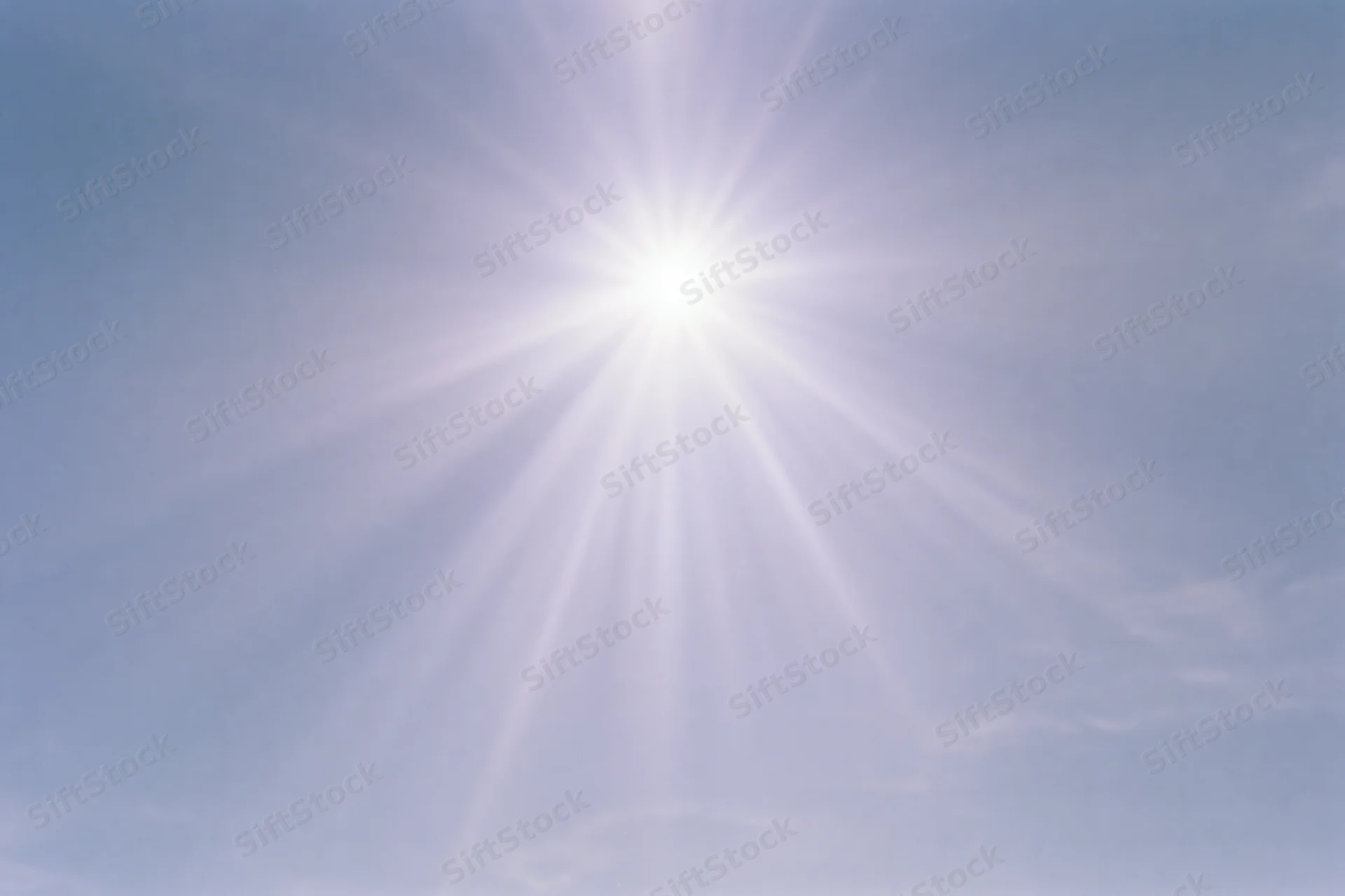 Intense sunburst radiating from upper center of clear blue sky