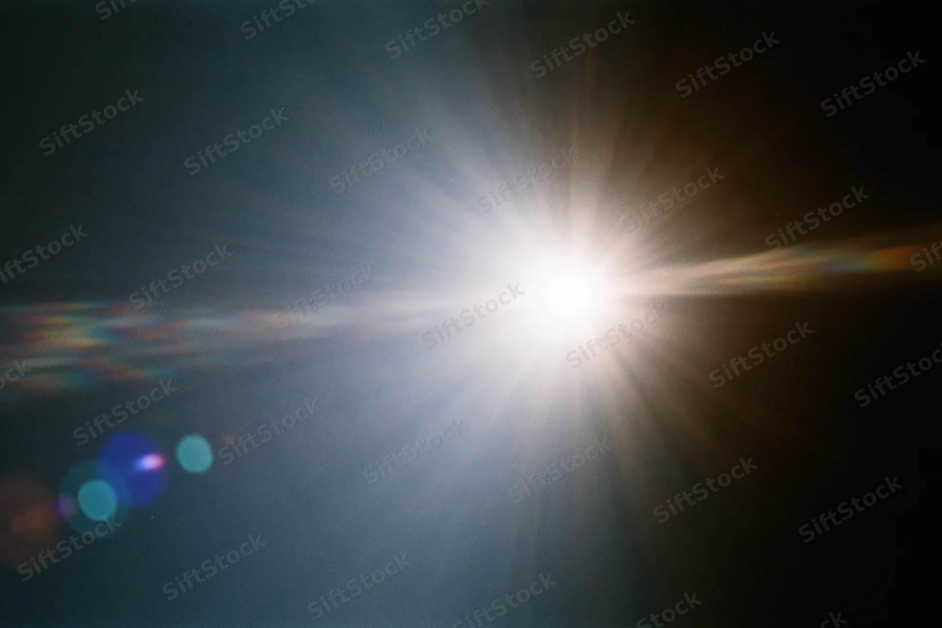 Intense white light source blazing against a near-black background with lens flare and rainbow streaks