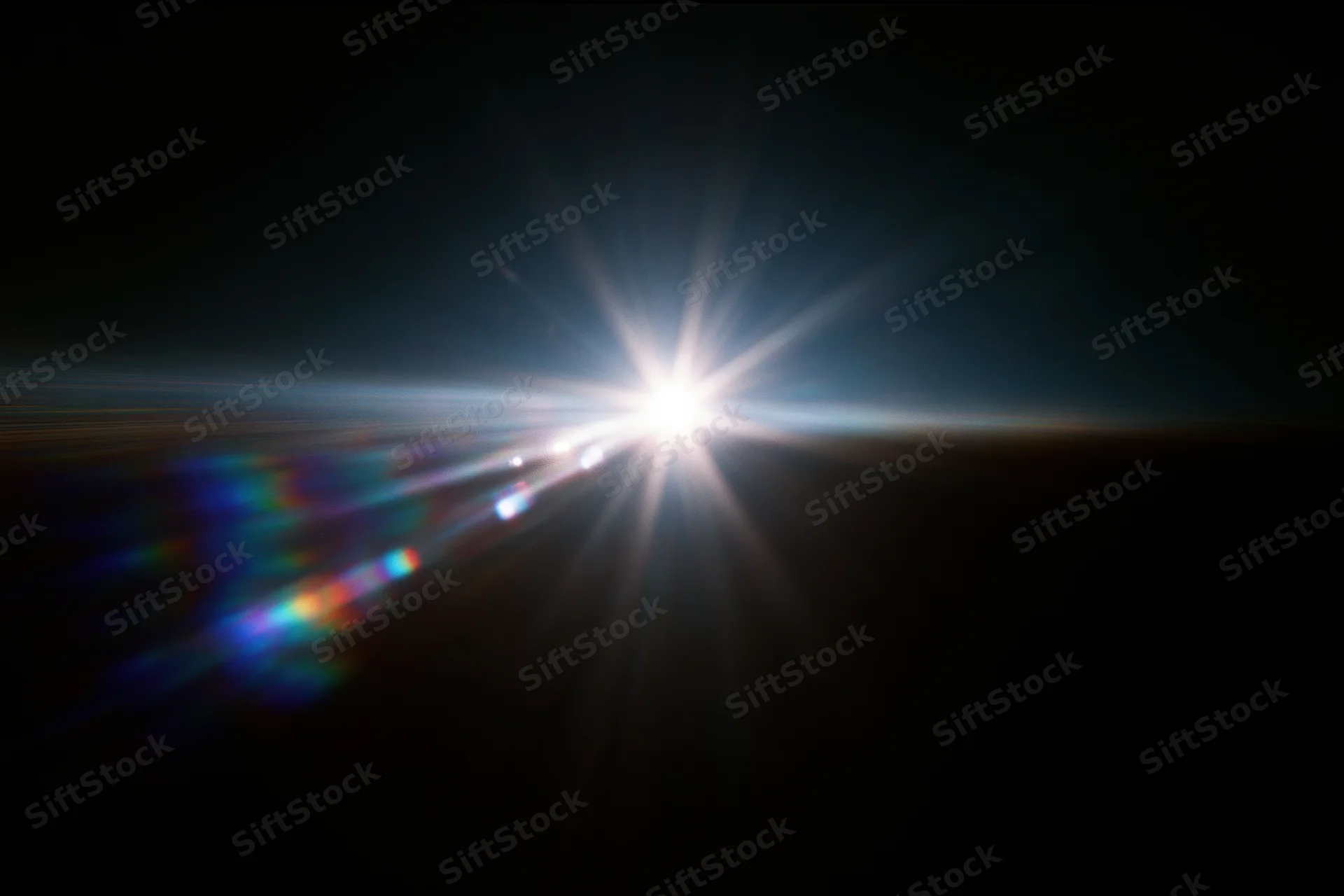Intense white light source blazing against a near-black background with lens flare and rainbow spectrum streaks
