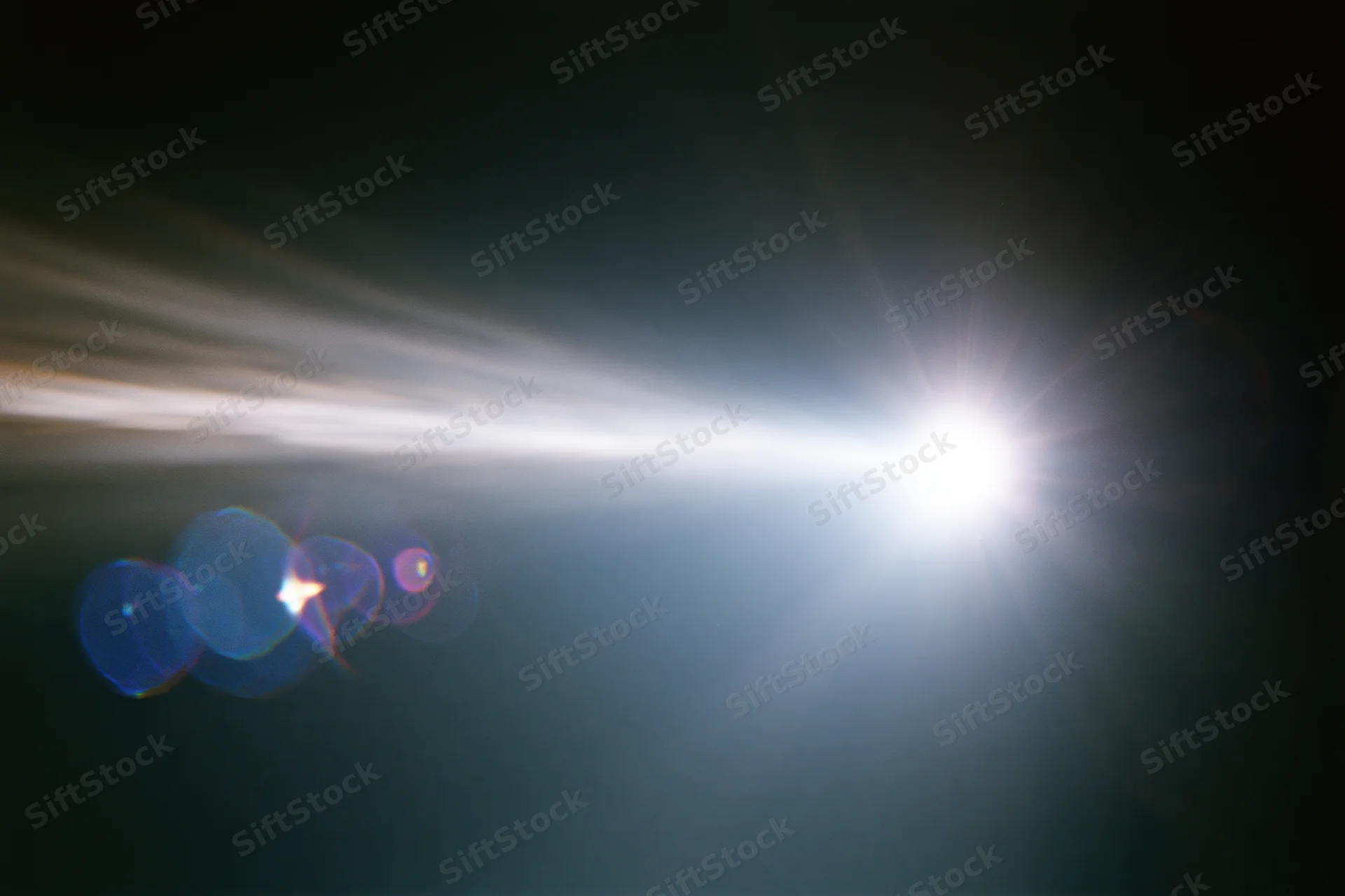 Intense white light source blazing against a near-black background with lens flare and bokeh effects