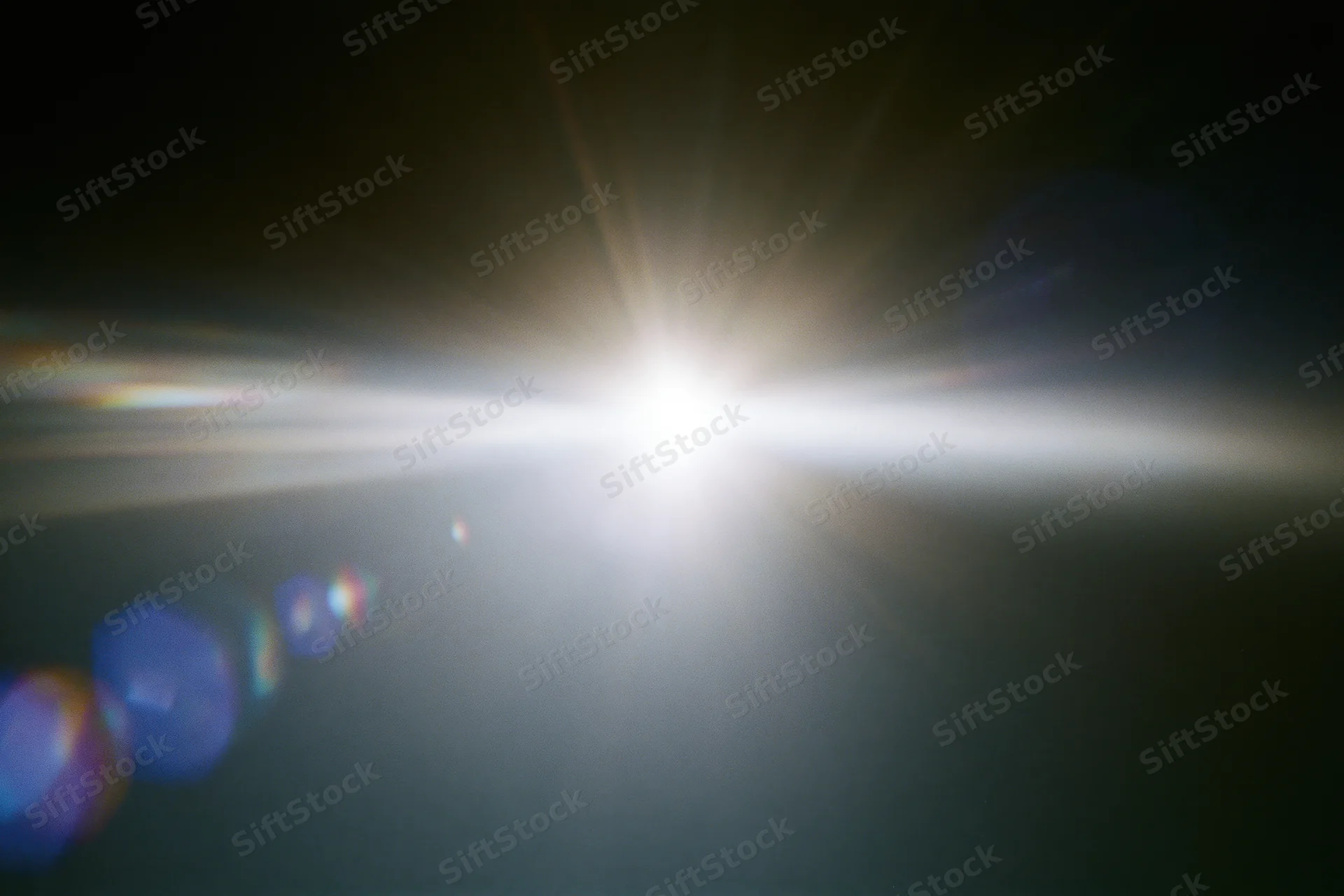 Intense white light source blazing against a near-black background with lens flare and bokeh effects
