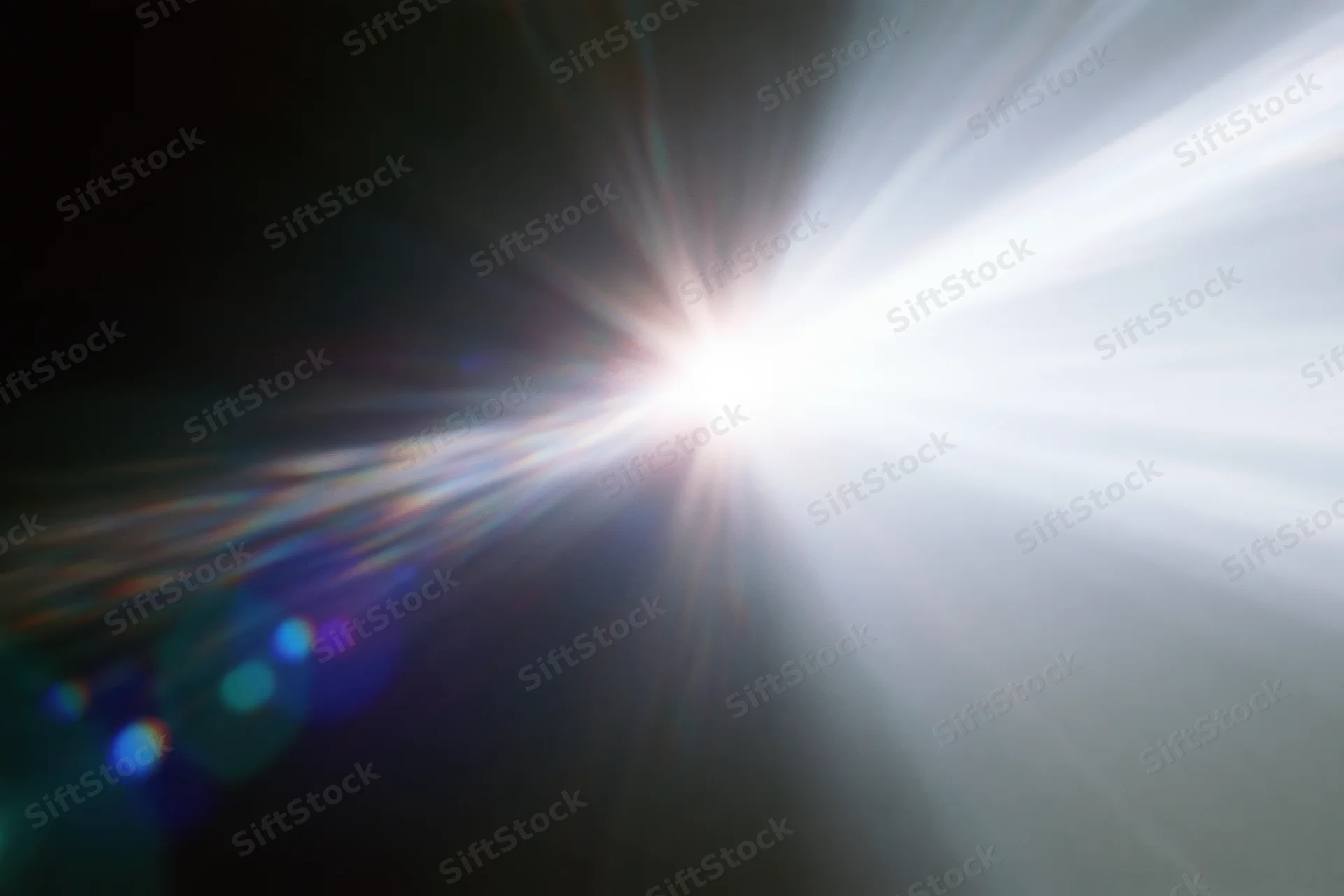 Intense white light source radiating bright beams against dark background with lens flare and bokeh effects