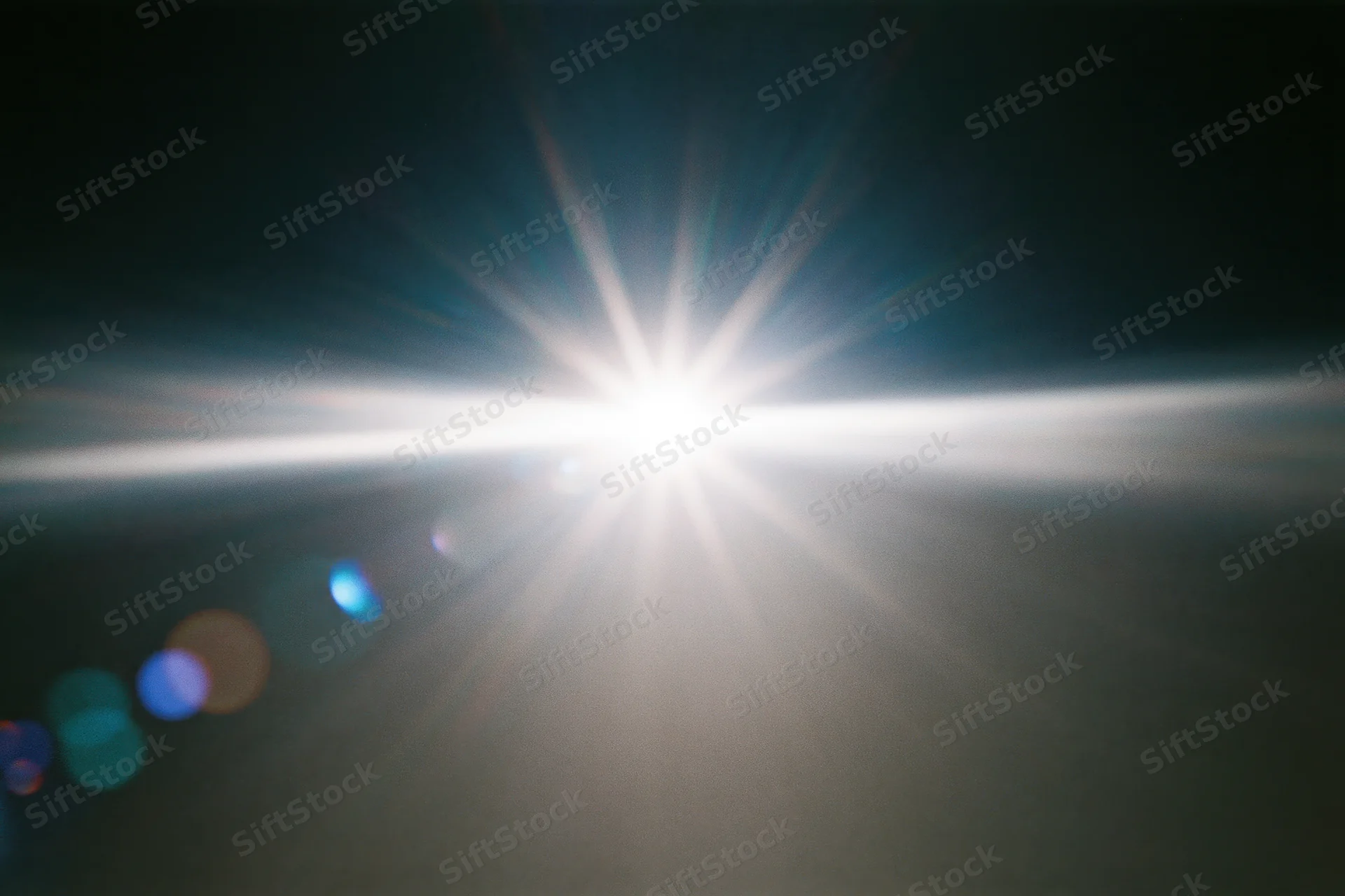 Intense white light source blazing against a near-black background with lens flare and bokeh circles