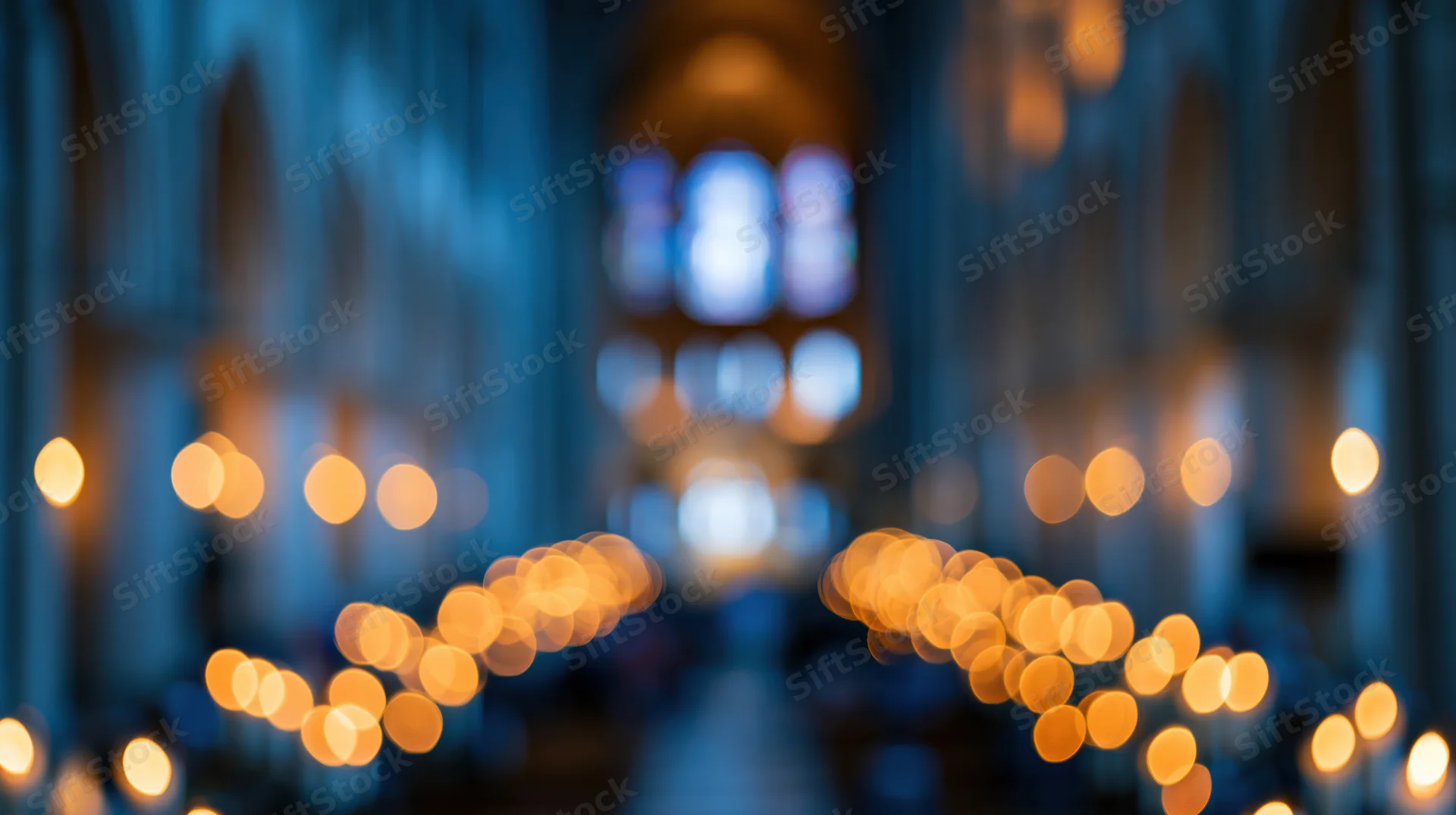 Blurred interior of a cathedral nave with glowing candles and stained glass windows