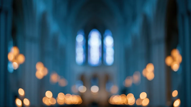 Blurred interior of a cathedral nave with glowing candles and stained glass windows
