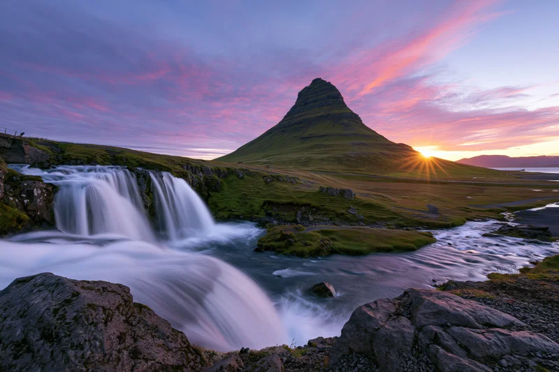 Kirkjufell mountain rising above a cascading waterfall at sunset in iceland
