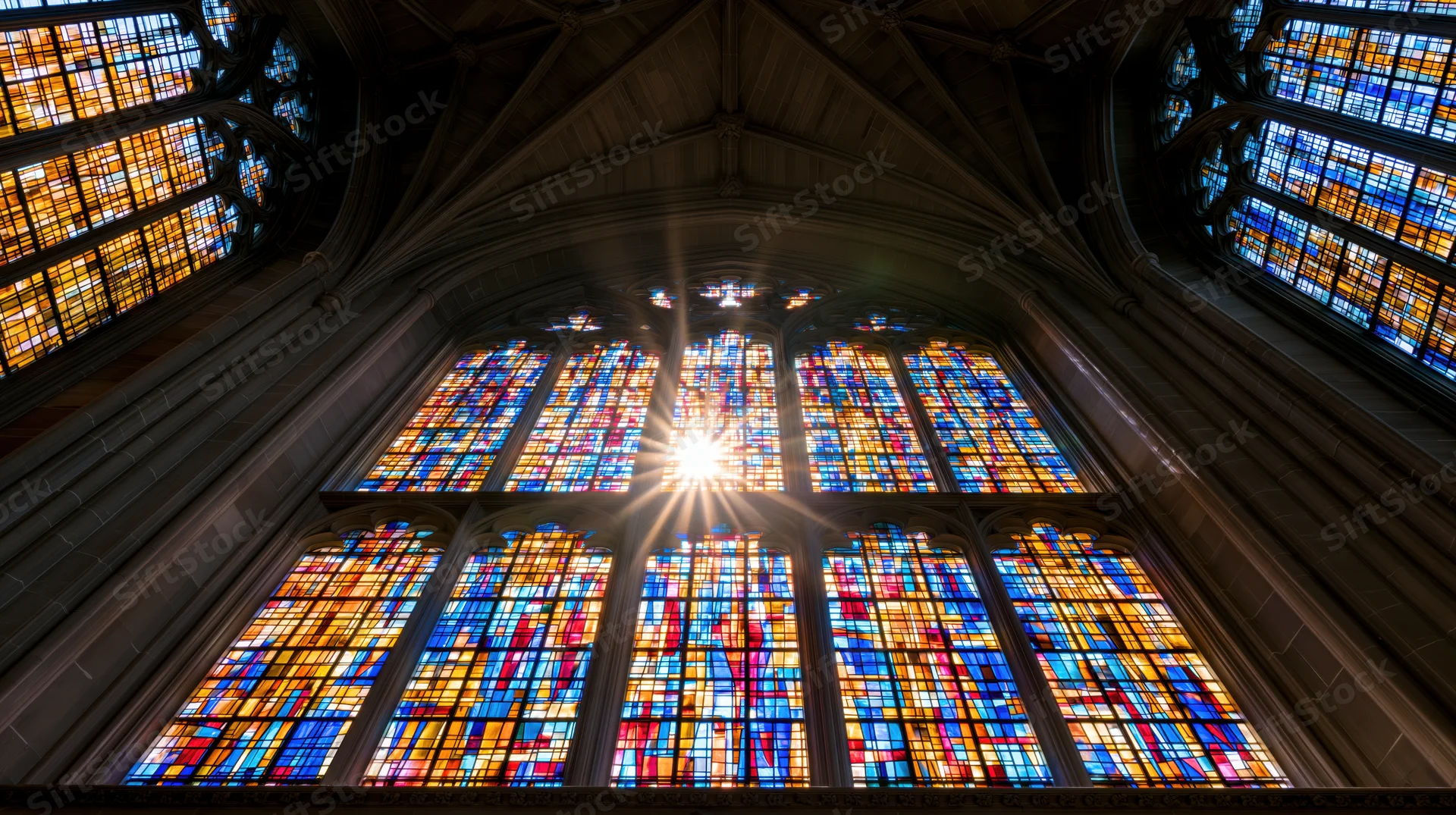 Large gothic stained glass window in cathedral interior illuminated by sunlight from below