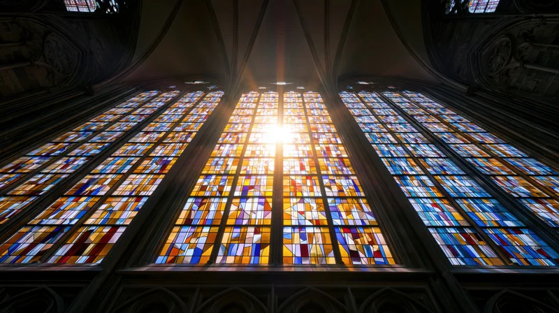 Large gothic stained glass cathedral window viewed from below with sunlight streaming through