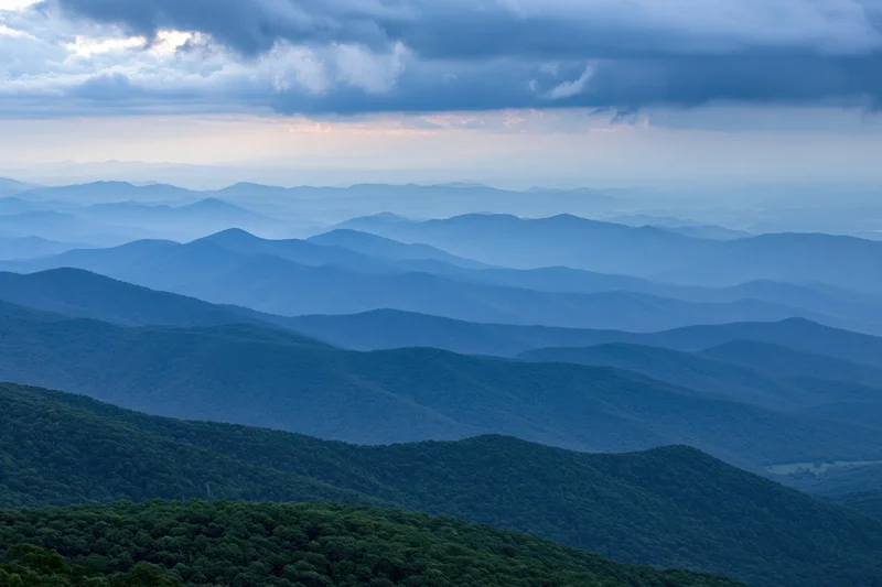 Layered appalachian mountain ridges receding into hazy distance with forested slopes under cloudy sky