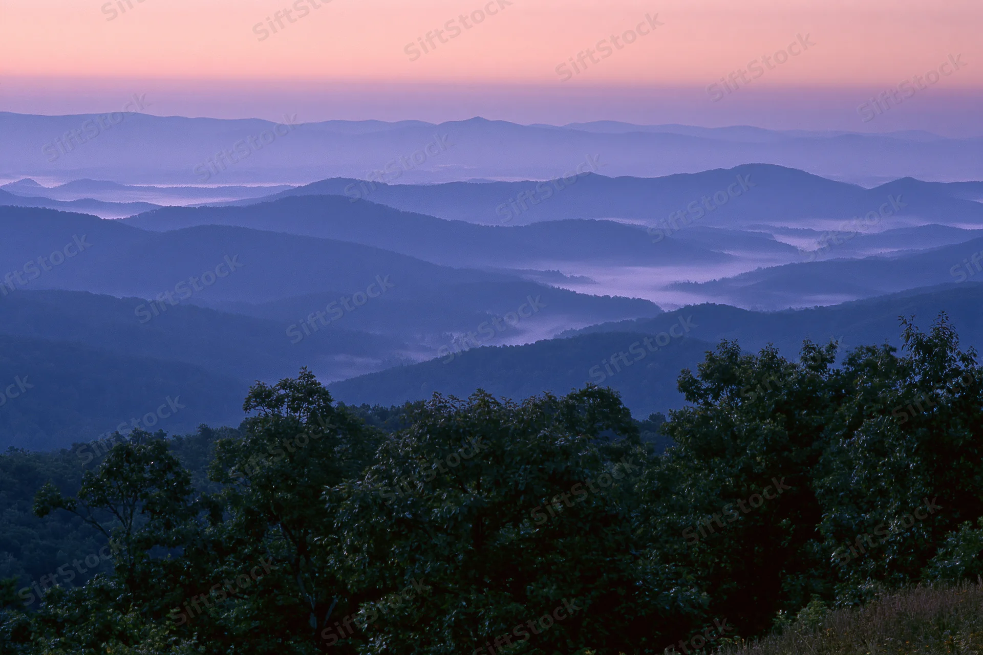 Layered appalachian mountain ridges receding into the distance under a twilight sky with fog in the valleys