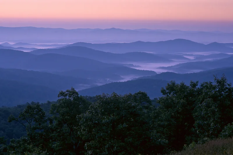 Layered appalachian mountain ridges receding into the distance under a twilight sky with fog in the valleys