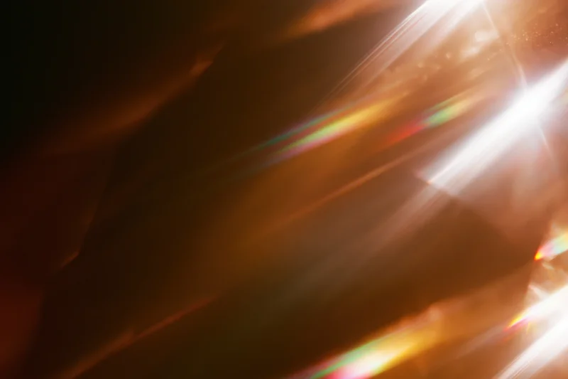 Light refracting through a glass crystal creating colorful beams and flares