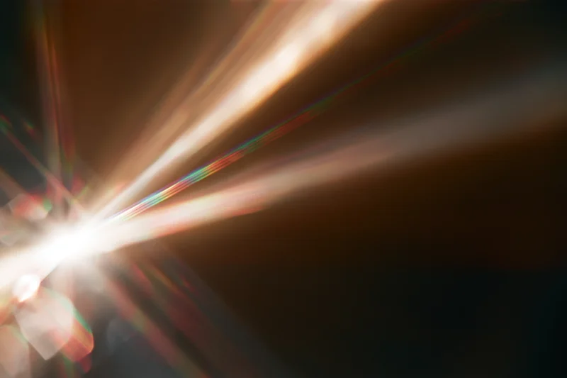 Light refracting through a glass crystal creating colorful beams and flares