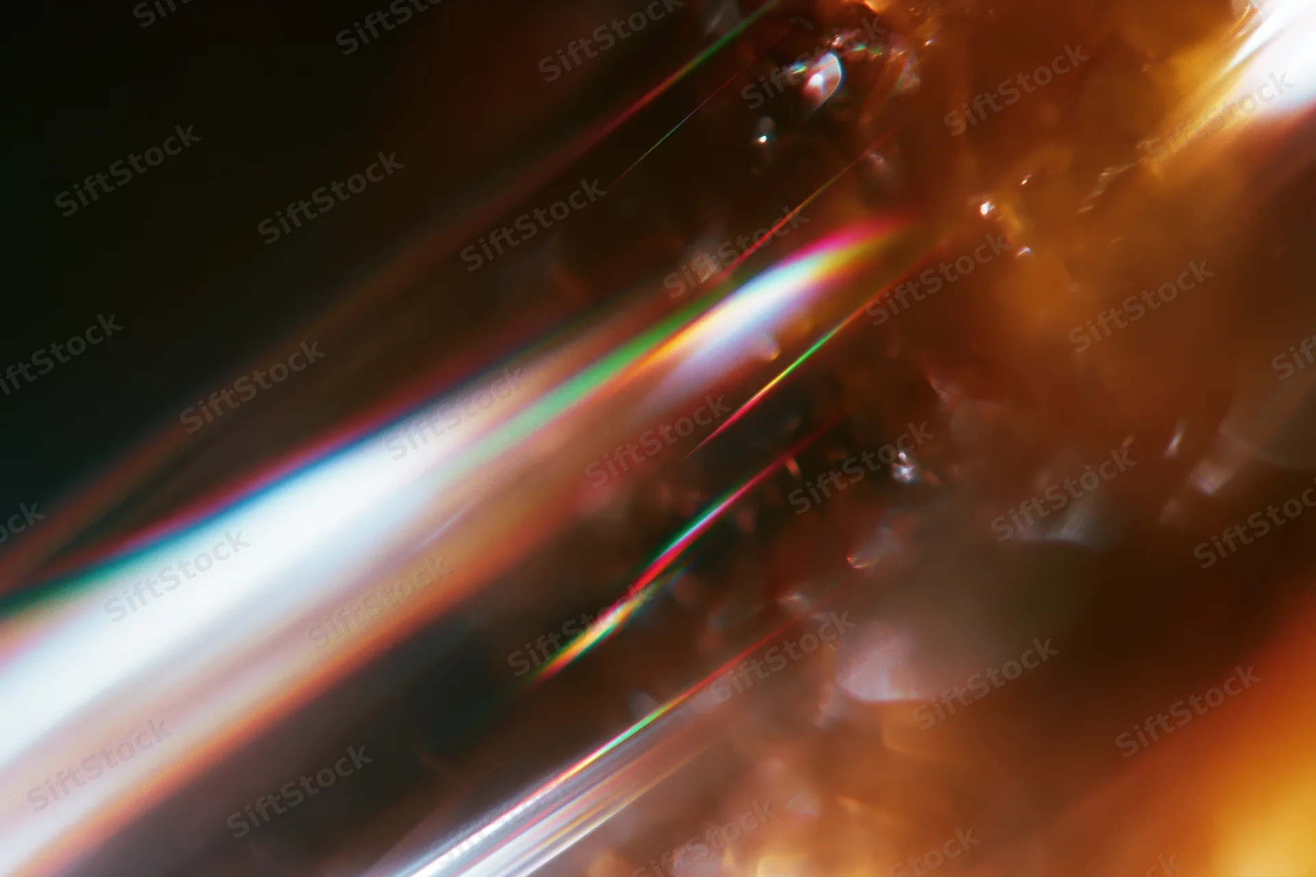 Light refracting through a glass crystal held close, creating a rainbow spectrum on a warm-toned surface