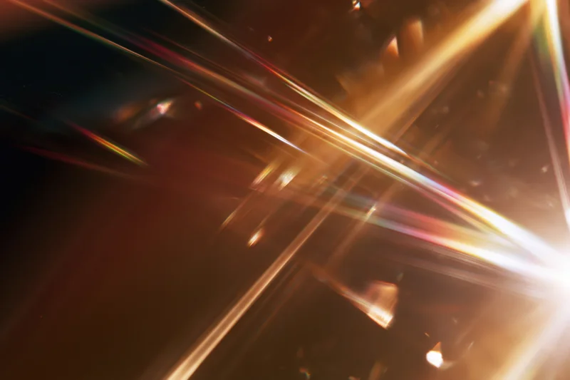 Light refracting through a glass crystal creating colorful beams and flares