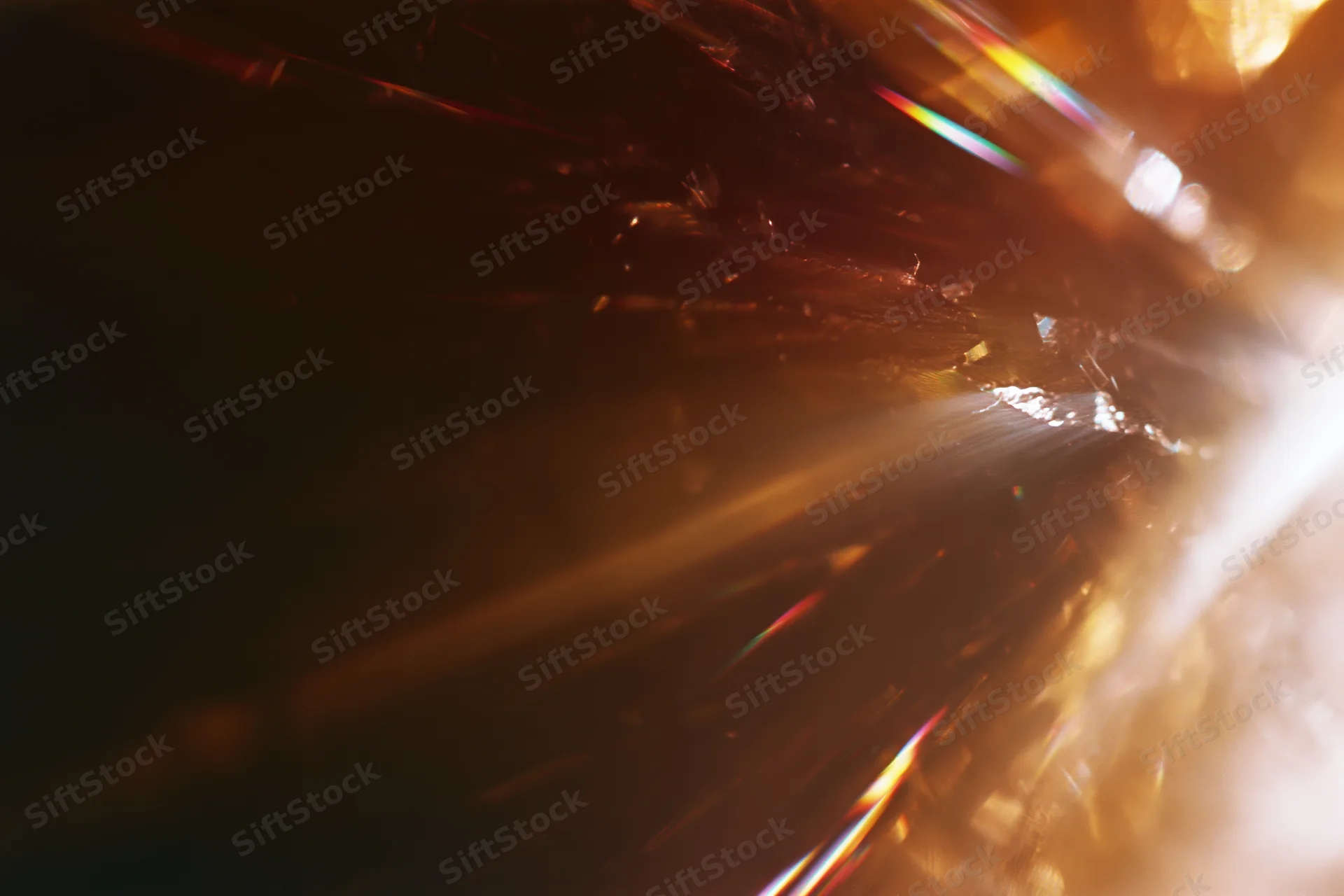 Light refracting through a glass crystal creating a rainbow spectrum in closeup view