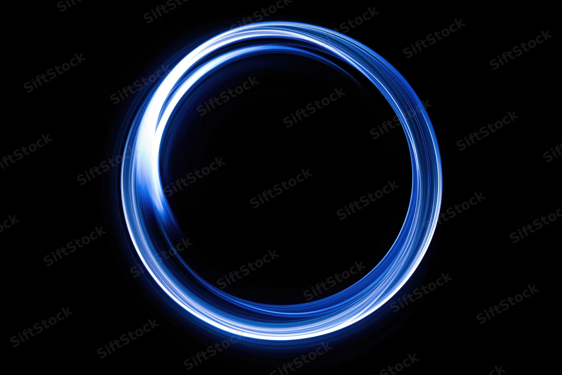 Glowing blue circular light trail formed by long-exposure light painting against black background