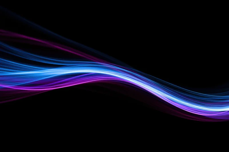 Glowing fiber-optic light waves flowing across a dark background in long-exposure light painting photography