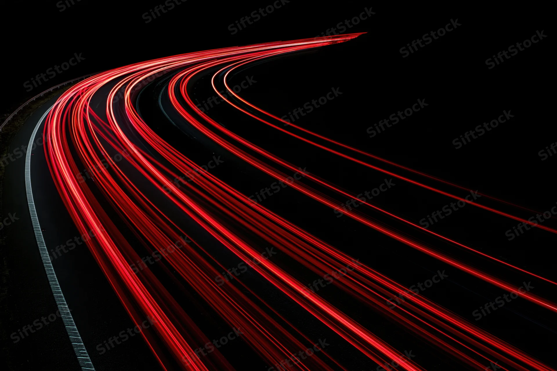 Red tail lights streaking along a curving highway at night
