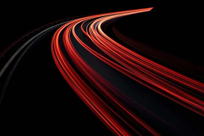 Curving highway at night with red tail light streaks from moving vehicles