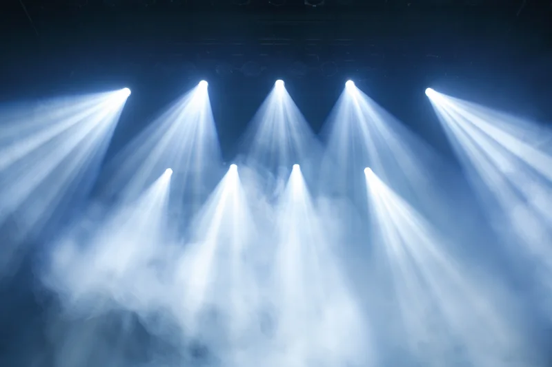 Multiple spotlights shining upward through haze on a stage