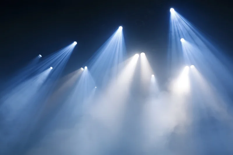 Multiple stage spotlights cutting upward through haze and smoke
