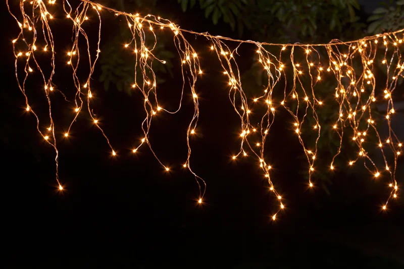 Multiple strands of warm white fairy lights draped loosely across a dark outdoor space at night