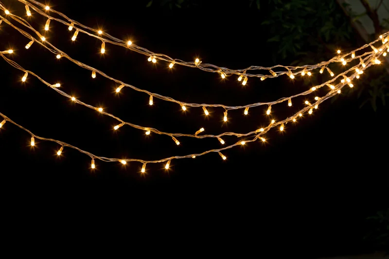 Multiple strands of warm white fairy lights draped loosely across a dark outdoor space at night