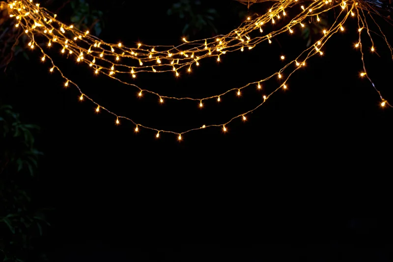 Multiple strands of warm white fairy lights draped loosely across a dark outdoor space at night