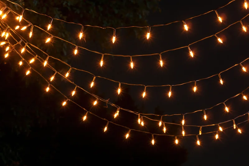 Multiple strands of warm white fairy lights draped loosely across a dark outdoor space at night