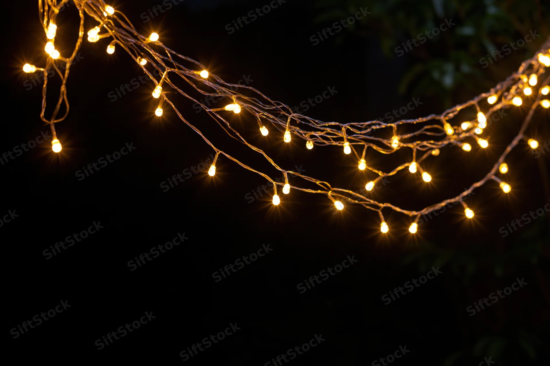 Multiple strands of warm yellow fairy lights draped loosely against a dark background with copyspace below