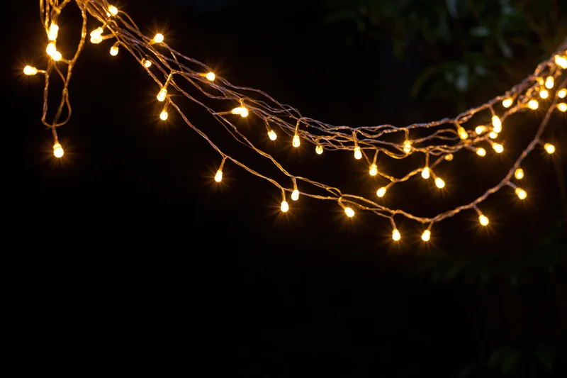 Multiple strands of warm yellow fairy lights draped loosely against a dark background with copyspace below