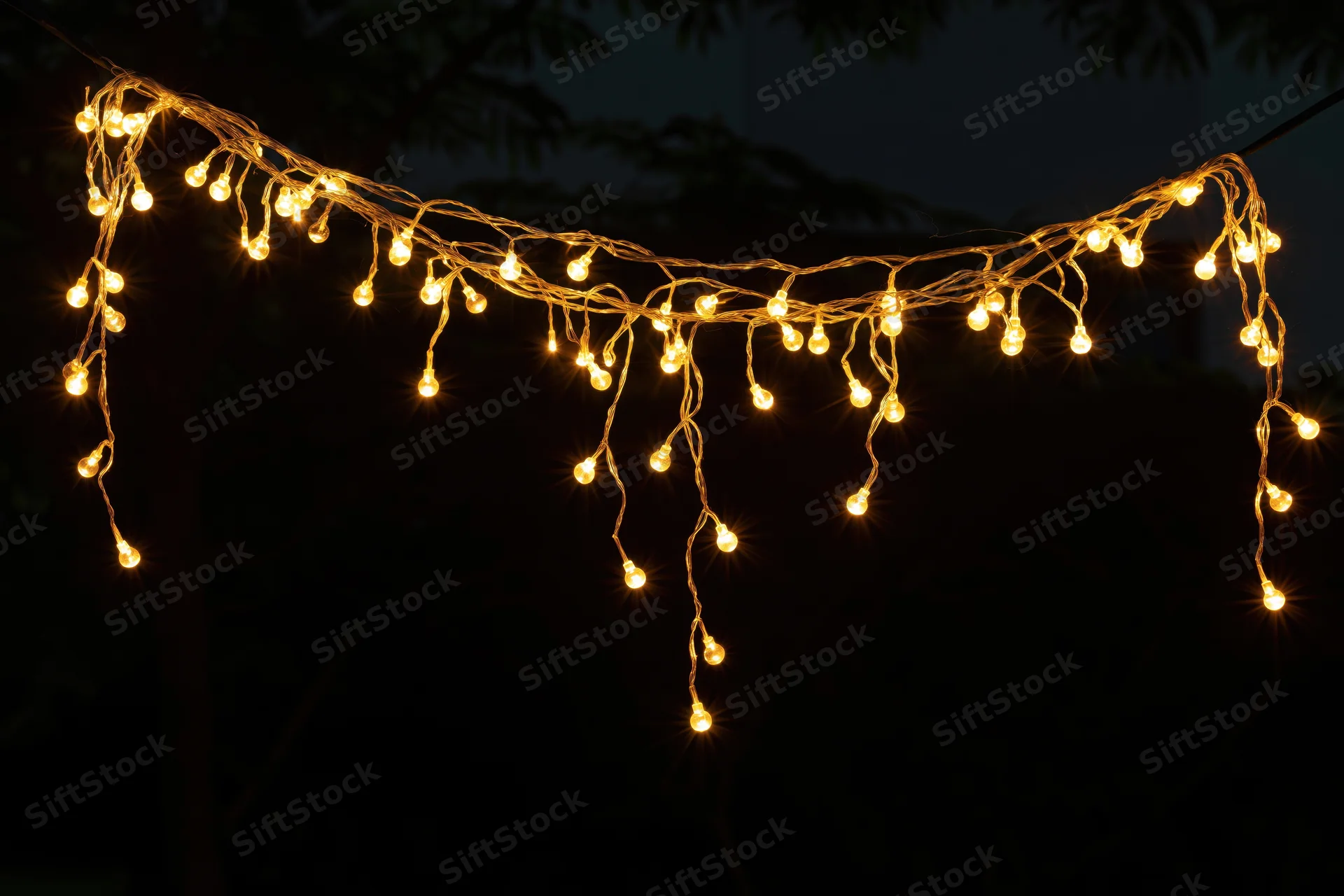 Multiple strands of warm yellow fairy lights draped loosely against a dark night background