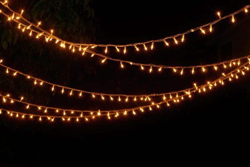 Multiple strands of warm yellow fairy lights draped loosely outdoors at night