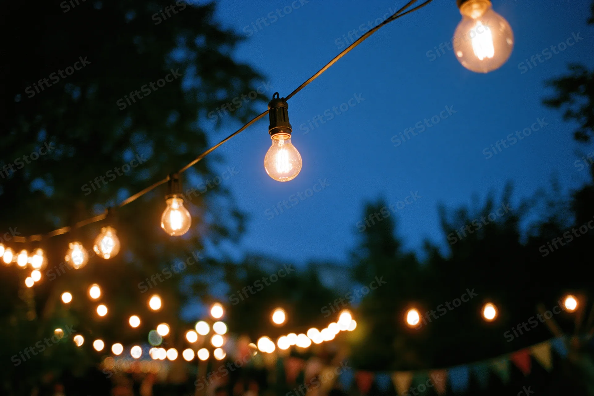 Warm edison string lights hanging across a garden patio at twilight