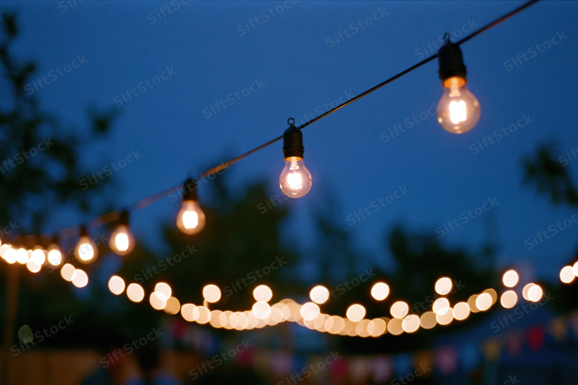 String lights with warm edison bulbs hanging across a garden patio at twilight