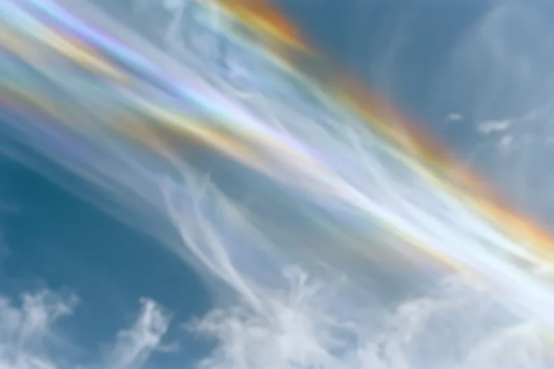 Pale blue sky with wispy clouds and lens prism rainbow effect