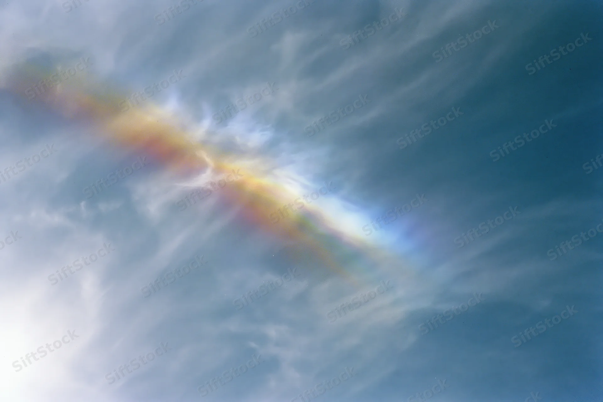 Overexposed sky with wispy cirrus clouds and iridescent lens flare effect