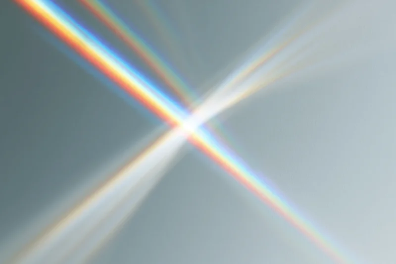 Prismatic light rays refracting across a plain pale grey-white background