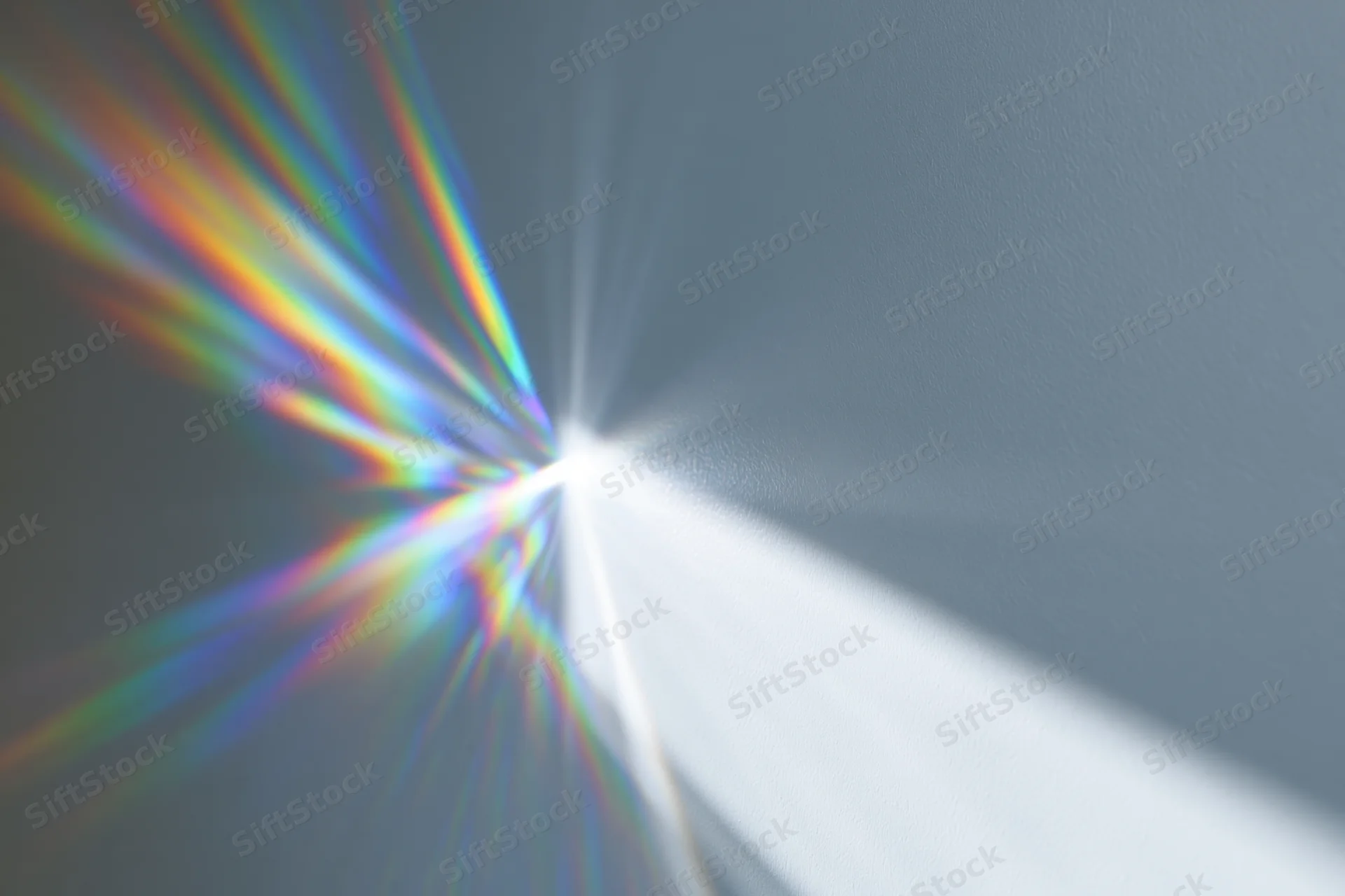 Prismatic light rays refracting across a plain pale gray-white wall